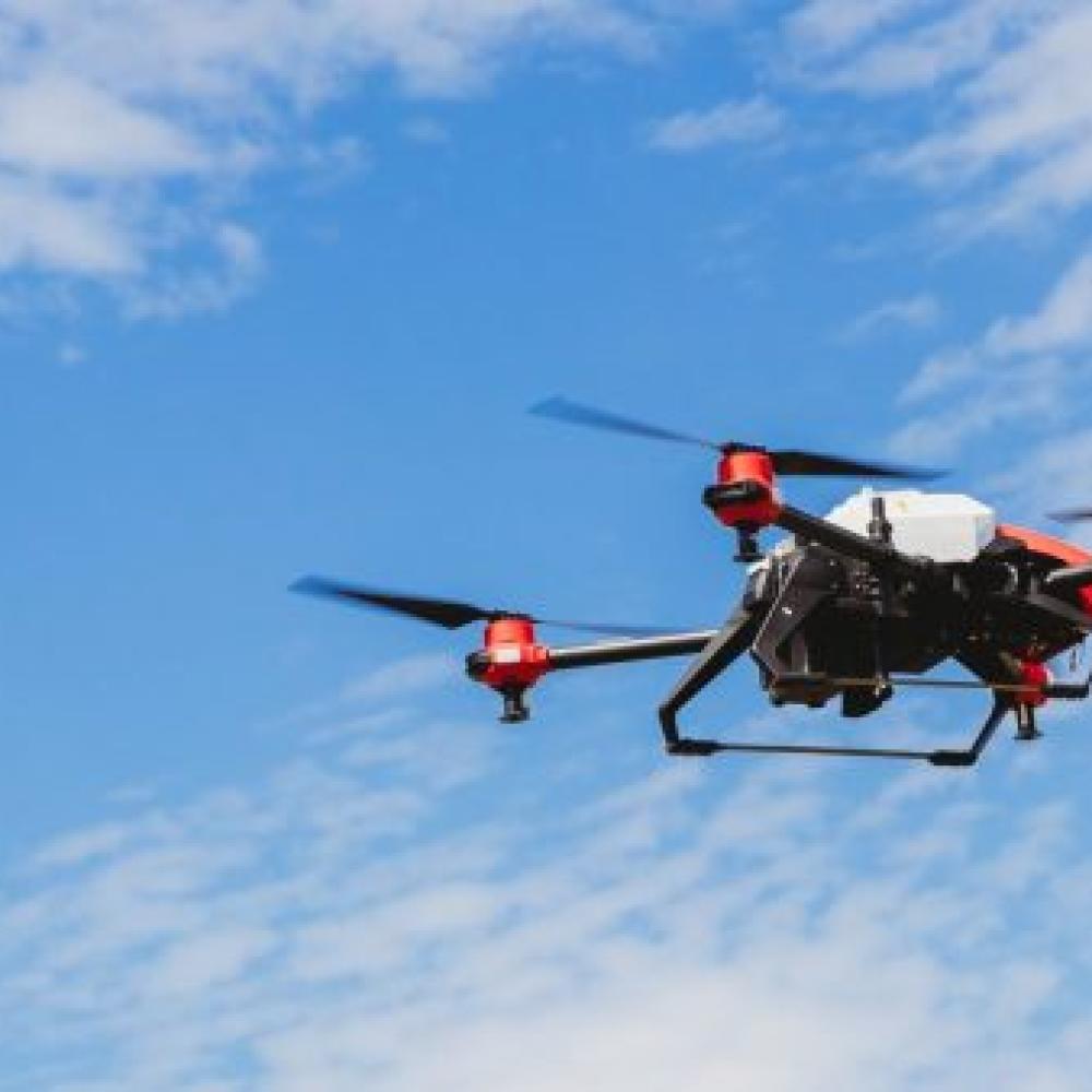 Red and black remote-controlled drone soaring through air. 